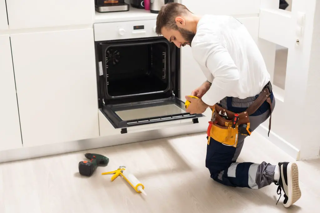 Oven Not Heating: Man Repairing Oven In Kitchen